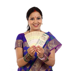 Cheerful traditional woman holding Indian currency