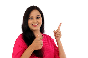 Happy young woman making thumbs up gesture against white backgro