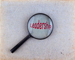 Leadership. Magnifying optical glass on old paper background