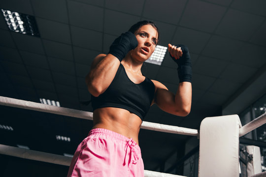 Young fitness beautiful brunette girl with boxing gloves on the ring. Young girl boxer. Boxing female trainer. Concept of active life.