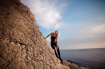 female rock climber climbs on rocky wall