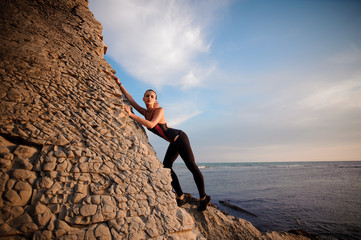 female rock climber climbs on rocky wall