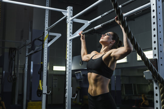 Concept: power, strength, healthy lifestyle, sport. Powerful attractive muscular woman CrossFit trainer do pull ups during workout at the gym