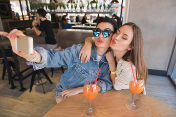 a woman in sunglasses doing selfie in a cafeteria