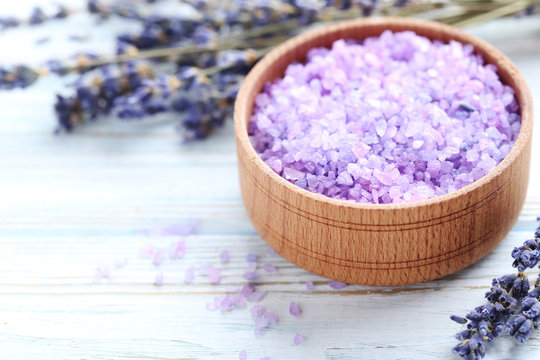 Bunch of lavender flowers with sea salt in bowl on white wooden