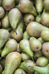 Stack of green pears on display at an outdoor farmers fruit market