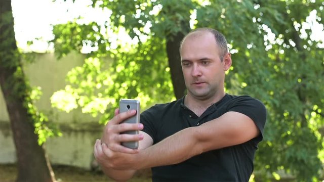 A man holding a phone like a gun and makes a selfie