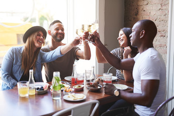 Black and white couples toasting drinks at table