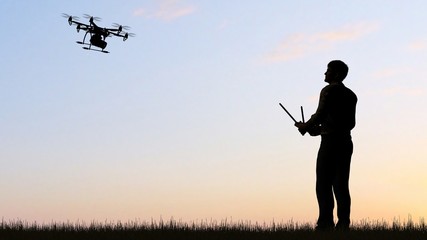 Naklejka na ściany i meble Man operating a drone at sunset using a controller