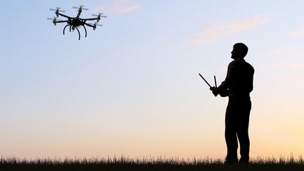 Fototapeta na wymiar Man operating a drone at sunset using a controller