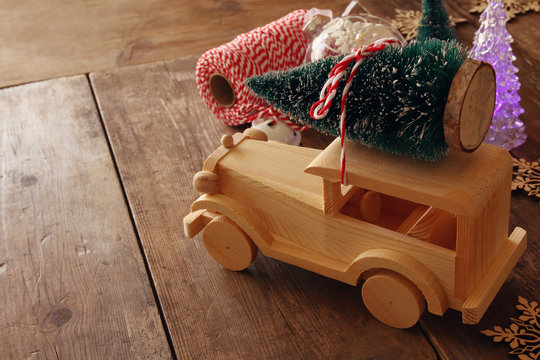 Wooden car carrying a christmas tree on wooden floor