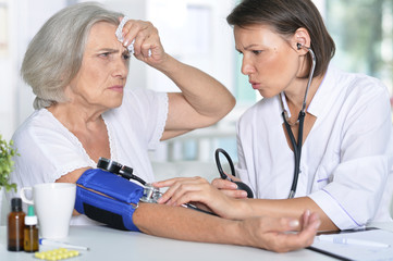 doctor measures the pressure her senior patient 