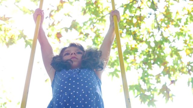 Cute little girl swinging in a park, sun flare