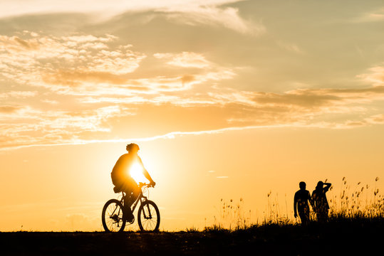 Silhouette of cyclist motion on sunset background