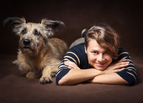 Beautiful young woman with a funny shaggy dog on a dark backgrou