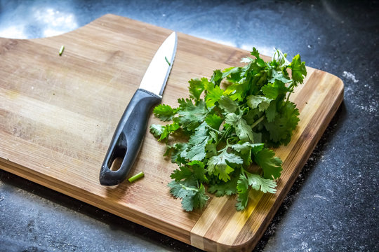 Cilantro Leaves / Coriander with a Knife on a Wooden  Cutting Board 