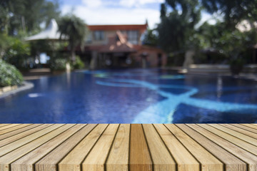 Wooden board empty table against of blurred swimming pool background. Perspective brown wood over swiming pool can be used for display or present your products.Mock up your products