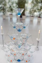 Beautiful wedding slide champagne for bride and groom indoors. Colorful glasses for alcohol with berries. Beauty of bridal interior for marriage. Bright bar for celebration
