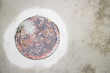 Rusty circle iron manhole cover on the concrete floor