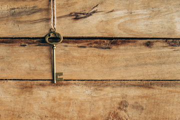 Old key hanging on brown wood with space.