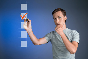 Young man t-shirt checking on checklist box. Blue background.