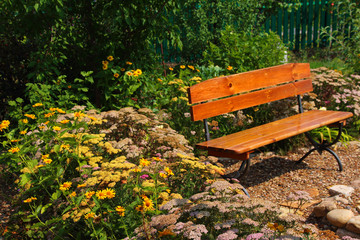 Garden rest area with a bench surrounded by blooming flowers and ornamental shrubs © argot