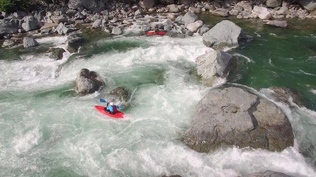 Drone Shot of Kayaker Charging Down Raging River on Sunny Day