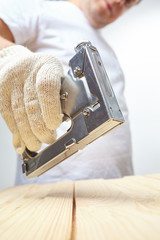 Male installer using stapler for wooden plank