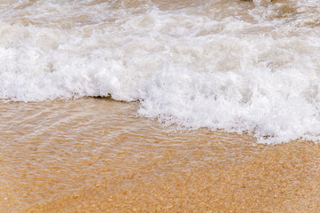Foam wave on sea close with beach background