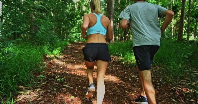 Athletic couple running together in the forest