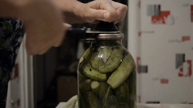 Woman pickling the green cucumbers in a jar using hand equipment. Home canning. Slow motion. Close-up.