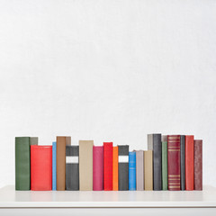stack of books on the white table near the wall