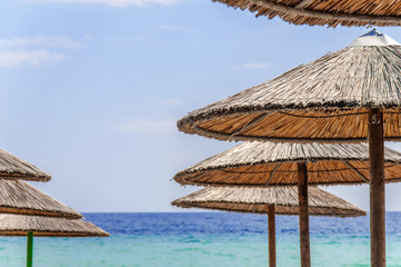Straw umbrella on beautiful beach background close