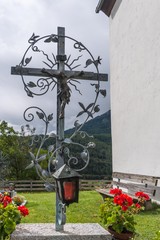 Kunstvolles Grabkreuz aus Schmiedeeisen mit Blumen und Laterne