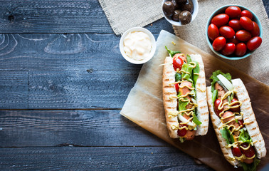 Hot dog with pickles, tomatoes and olives