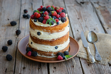 Tasty cake with strawberry, raspberry and blackberry on a wooden table