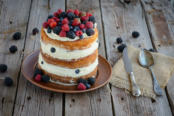 Tasty cake with strawberry, raspberry and blackberry on a wooden table