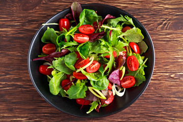 Baby leaves salad with cherry tomatoes and leek rings