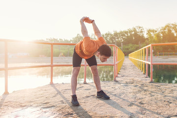 Young athlete holding his arms behind back and stretching outdoors