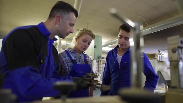 Professional teacher showing carpentry machinery to students