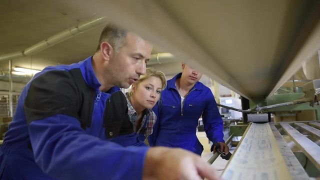 Professional teacher showing carpentry machinery to students