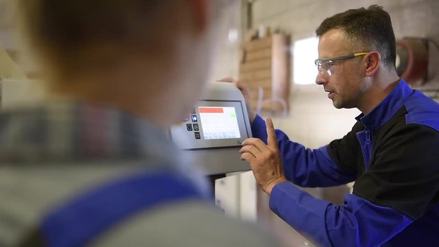 Professional teacher showing carpentry machinery to students