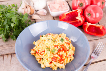 Risotto with chicken, tomatoes, bell pepper, onion, parsley and garlic on a blue plate on a wooden background