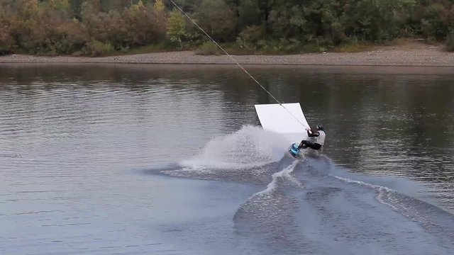 man on a wakeboard doing a back flip from a springboard. Beautiful and dangerous stunt. wakepark