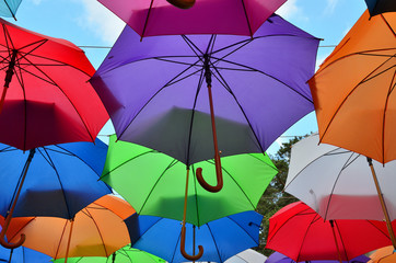 Opened colorful umbrellas with parts of spring blue sky with clouds