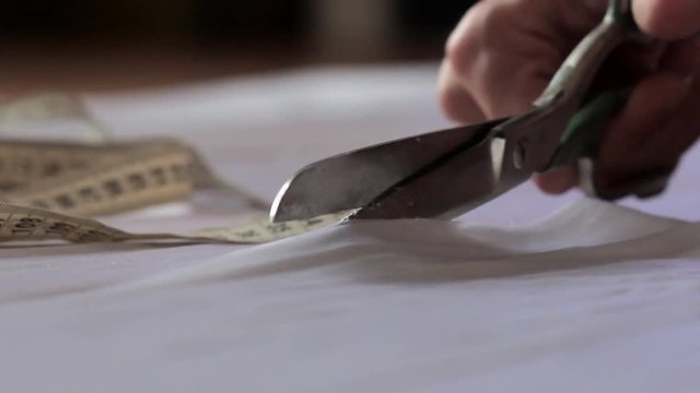 Close up of hands with scissors cutting white material
