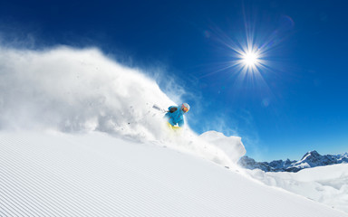 Naklejka na ściany i meble Skier skiing downhill in high mountains