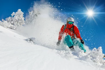 Tuinposter Wintersport Skiër skiën bergafwaarts in hoge bergen