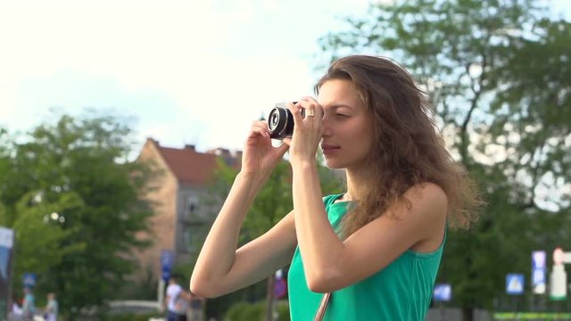 Girl standing in the town and doing photos on old camera, steadycam shot, slow motion shot
