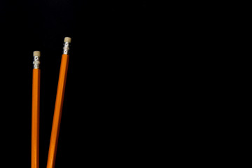 Two pencils on dark surface